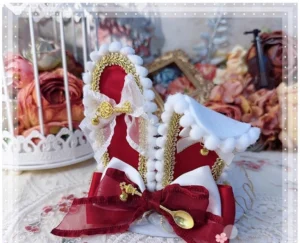 Burgundy red lolita bunny ear top hat headdress with satin bow and gold tableware ornament on vintage floral lace background, front flat view
