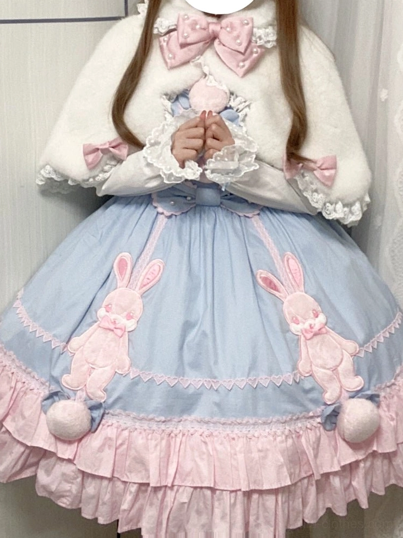 Lolita cape with pink bow paired with blue bunny print dress and pom-pom details front model view