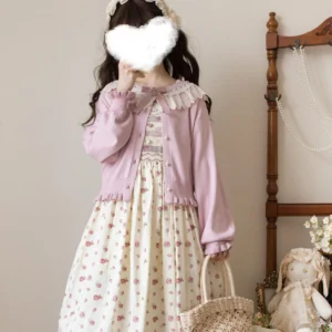 Model wearing deep pink retro kawaii lolita cardigan with ruffled lace Peter Pan collar paired with floral print lolita dress in cozy vintage indoor setting