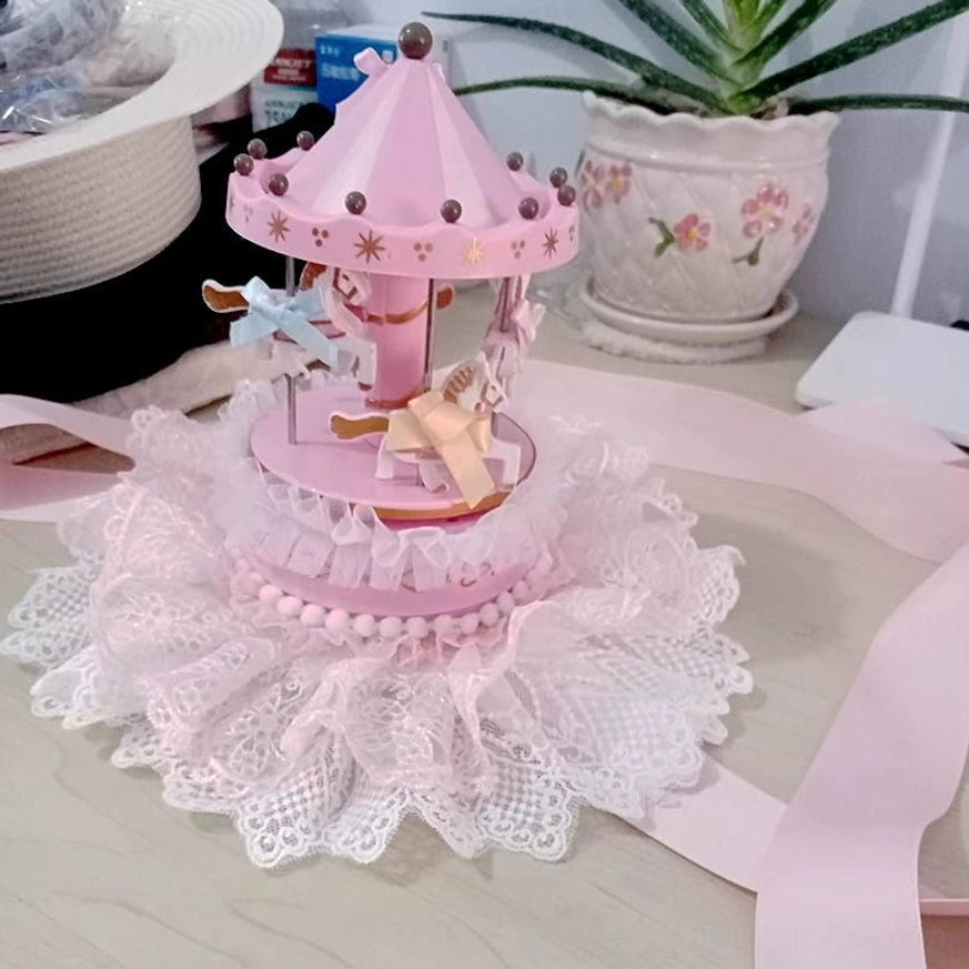 Pink handmade lolita carousel mini top hat flat lay on desk with potted plant featuring pink white color scheme lace ruffle trims gingham ribbons