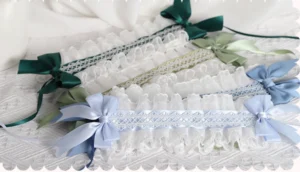 Multi-color sweet lolita cat ear hairband collection overhead flat lay display showing sage green dark green light blue and wine red satin bows with white ruffled eyelet lace and embroidered mesh panels