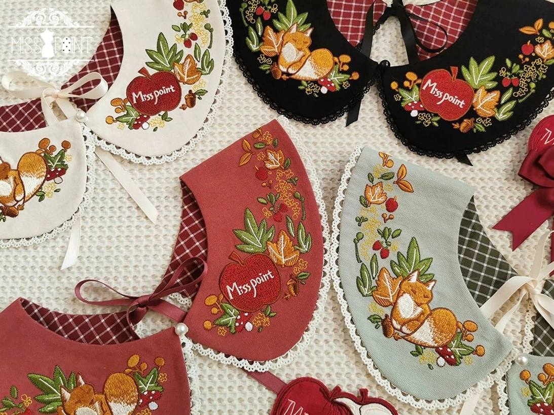 Close-up overhead view two series embroidered fake collars mint green forest plant embroidery brick red fox pattern black collars with lace edge trim flat lay