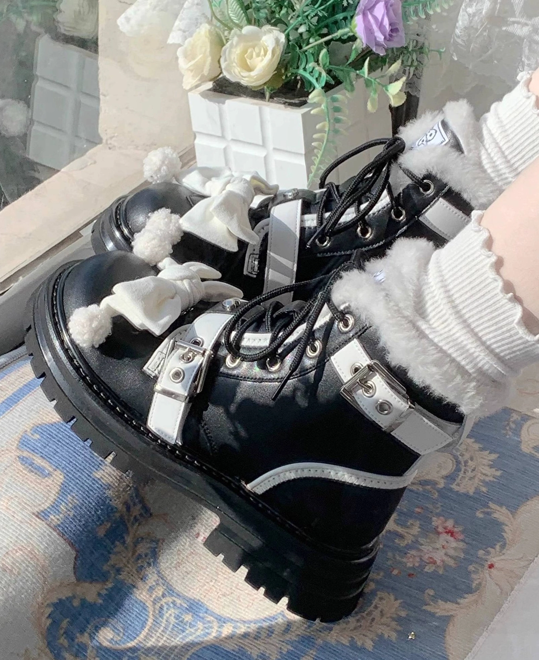 Lolita winter combat boots low-angle front view fuzzy fur collar lace-up design silver buckle straps black leather upper indoor windowsill