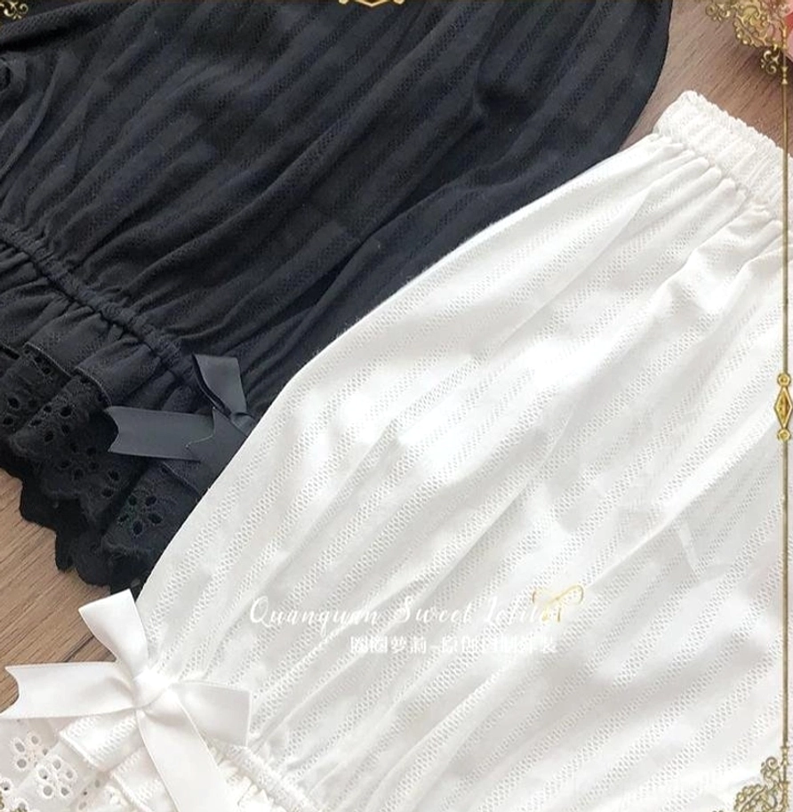 Overhead close-up shot of black and white premium lolita cotton bloomers showcasing black variant with delicate black decorative bows, white variant with prominent white ribbon bows, multi-layer ruffled embroidered lace hems, and authentic lolita aesthetic details