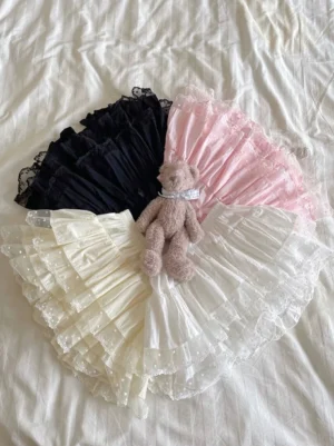 Multi-color Lolita cotton bloomers tiered ruffle flat lay display showing all color options black ivory white and pink with sheer polka dot lace trim and teddy bear decoration on bedding surface