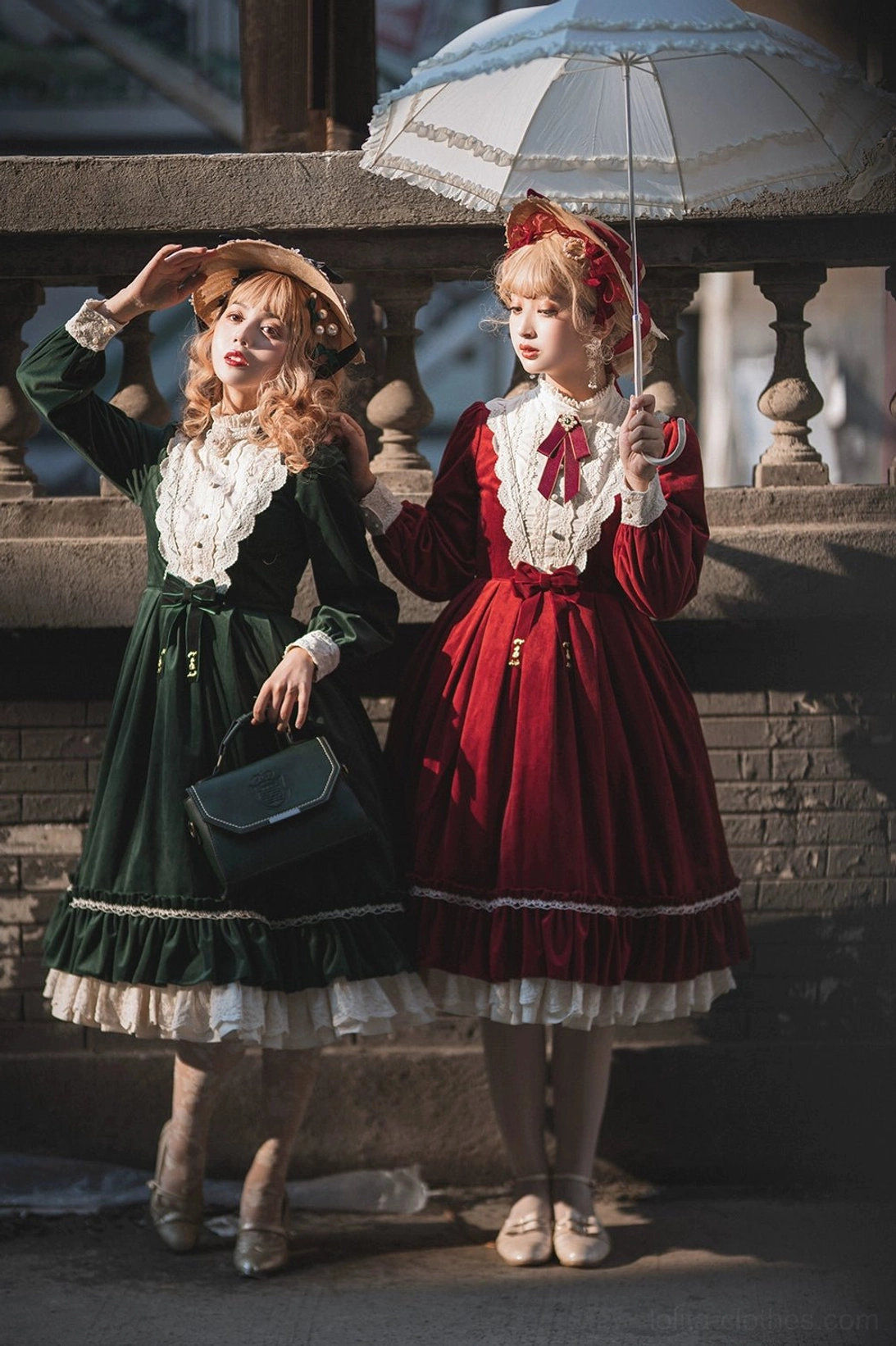 Vintage velvet lolita OP dress front side group shot stone balcony area one model holding lace parasol both models vintage hair accessories hats leather handbag green dress