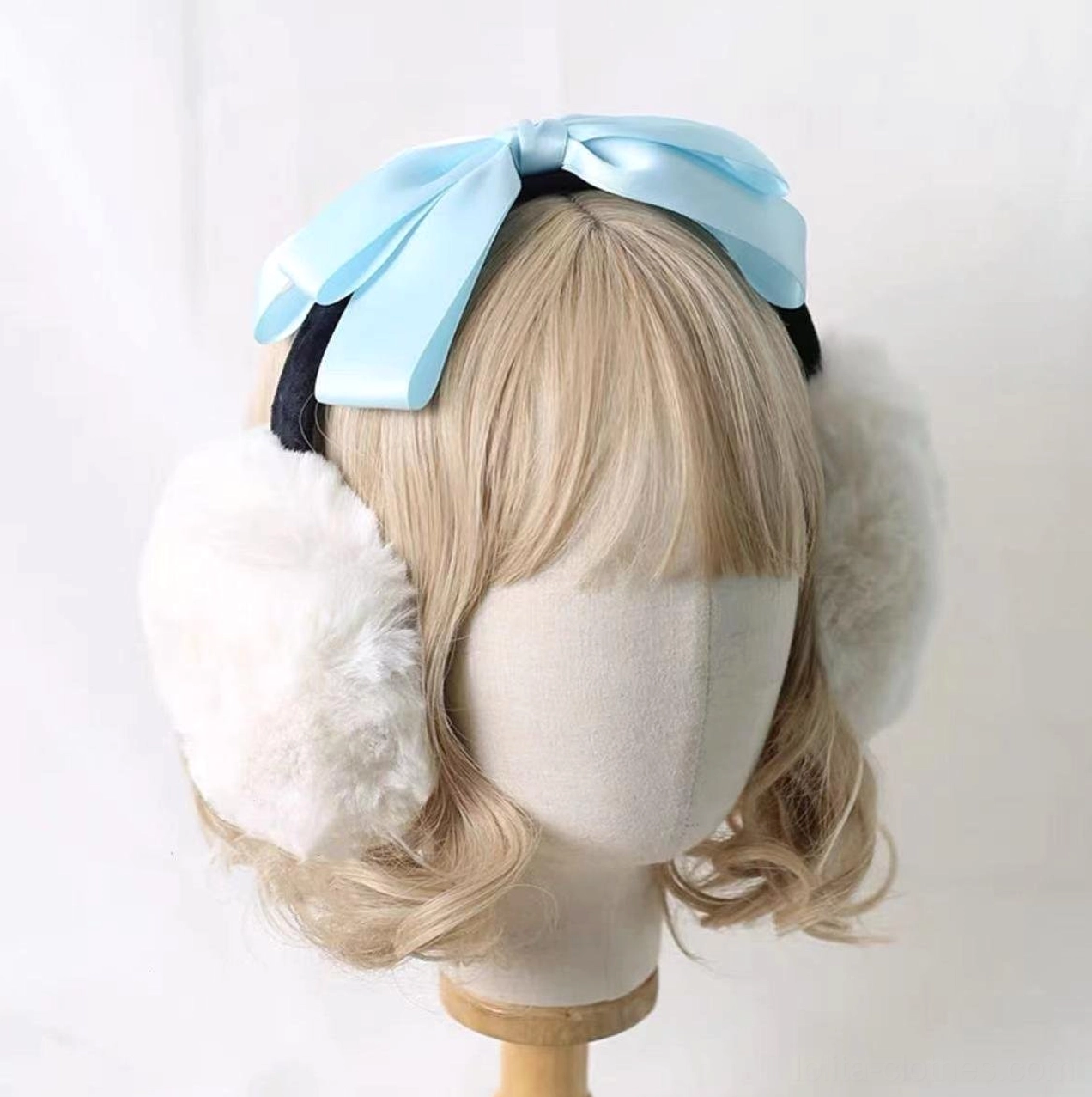 Lolita plush earmuff headdress styled on mannequin with pastel light blue satin bow, white fuzzy earmuff cups, black headband strap, cute design