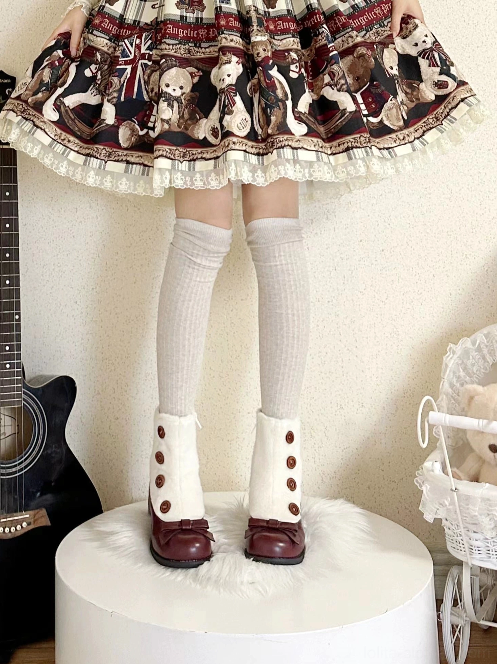 Lolita fashion model wearing winter boots with faux fur cuff bow vamp paired with lolita skirt knee-high socks guitar carriage studio backdrop