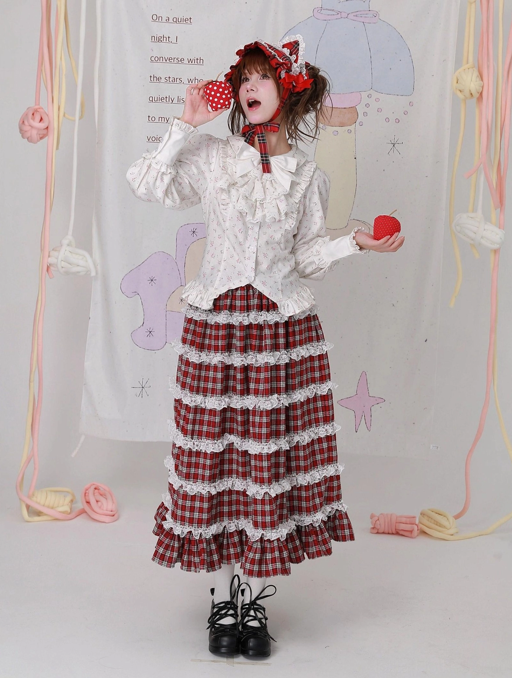 Romantic Lolita styling with floral cotton blouse and multi-layered lace hem plaid maxi skirt - model posing with strawberry props, wearing bonnet and black platform Lolita shoes