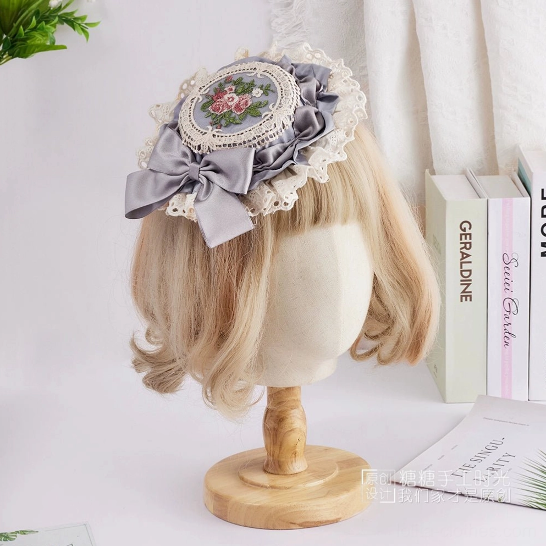 Charming Lolita headpiece featuring dusty lavender satin bow, blue floral hand-embroidery detail, and delicate white lace border on miniature top hat silhouette