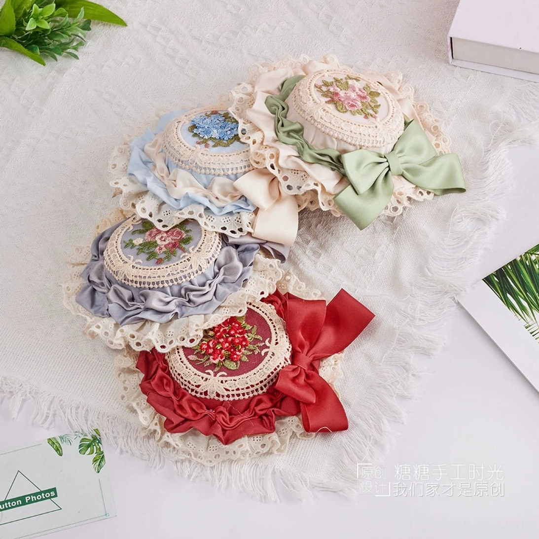 Lolita miniature top hat displaying secure clip fasteners and intricate floral embroidery design on white lace trimmed hat base