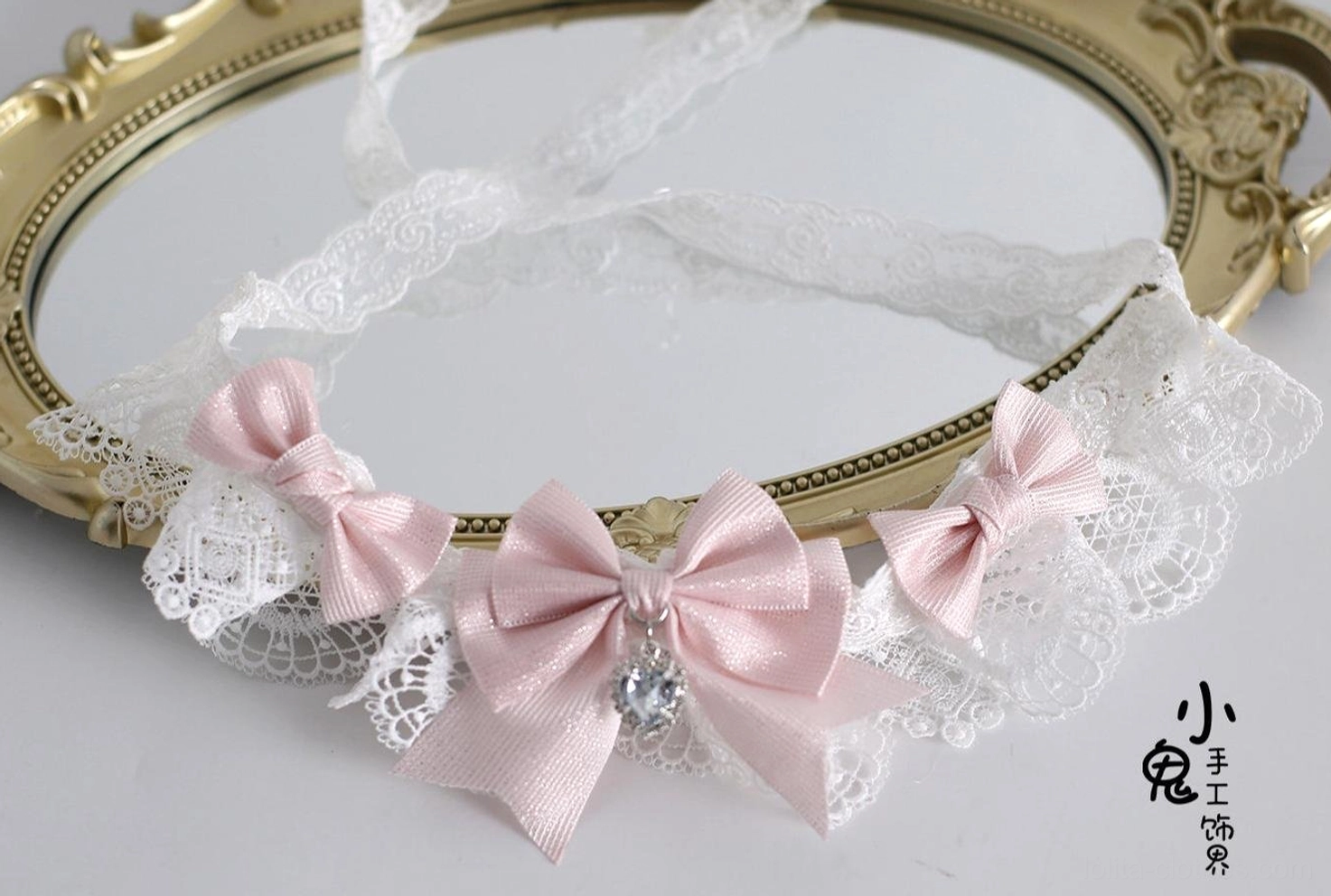 Lolita hair accessories flat lay display featuring choker, hairbow clips, and decorative pieces on mirrored surface with white lace and pink satin details