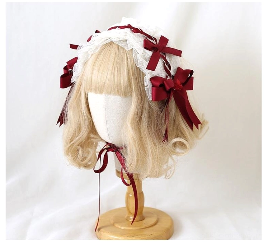 Lolita hairband headdress top-front view on wooden display stand showing white ruffled lace edges with wine-red bows and adjustable chin fixing strap