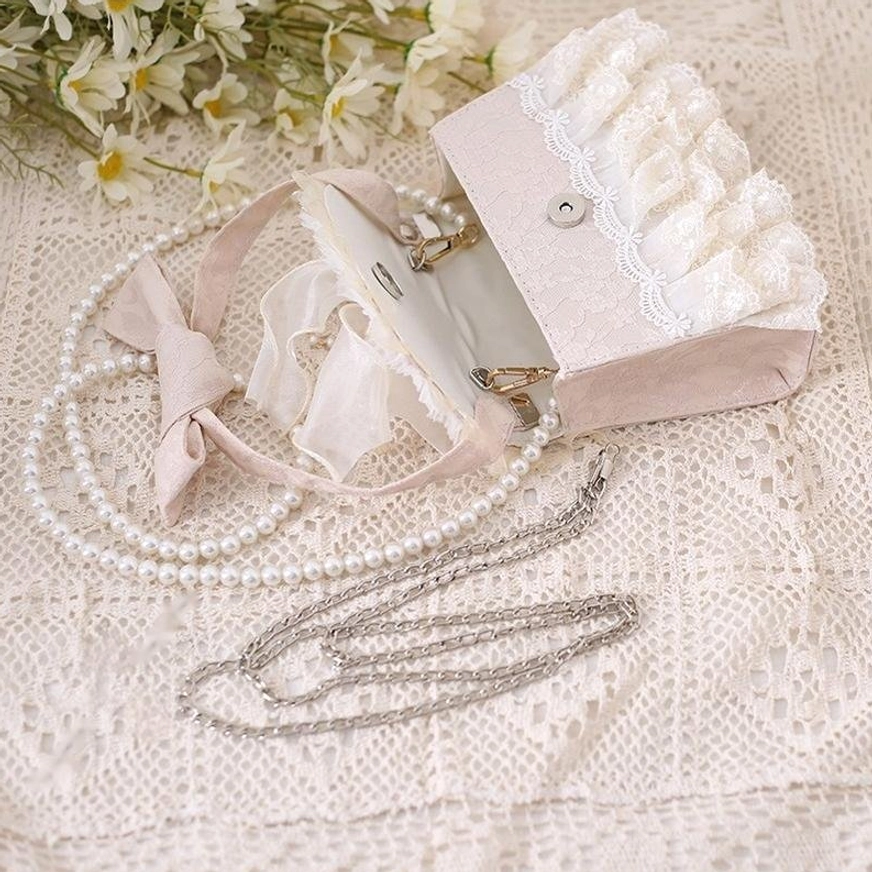 Opened lolita tea party handbag showing interior with pearl chain metal chain and velvet bow strap magnetic lock detail