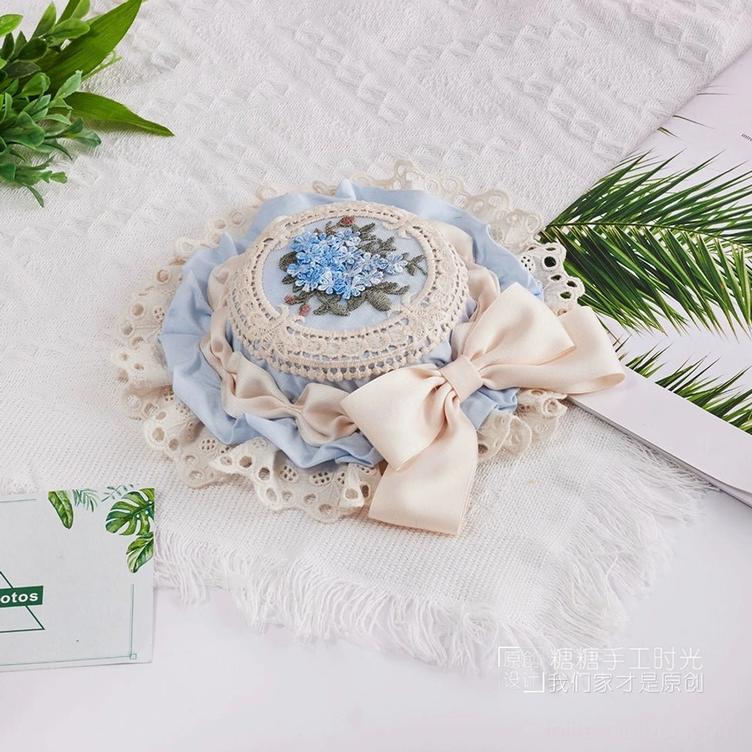 Charming Lolita headpiece featuring petite top hat with hand-embroidered floral center, coordinating satin ribbon bow, and fine white cotton lace trim