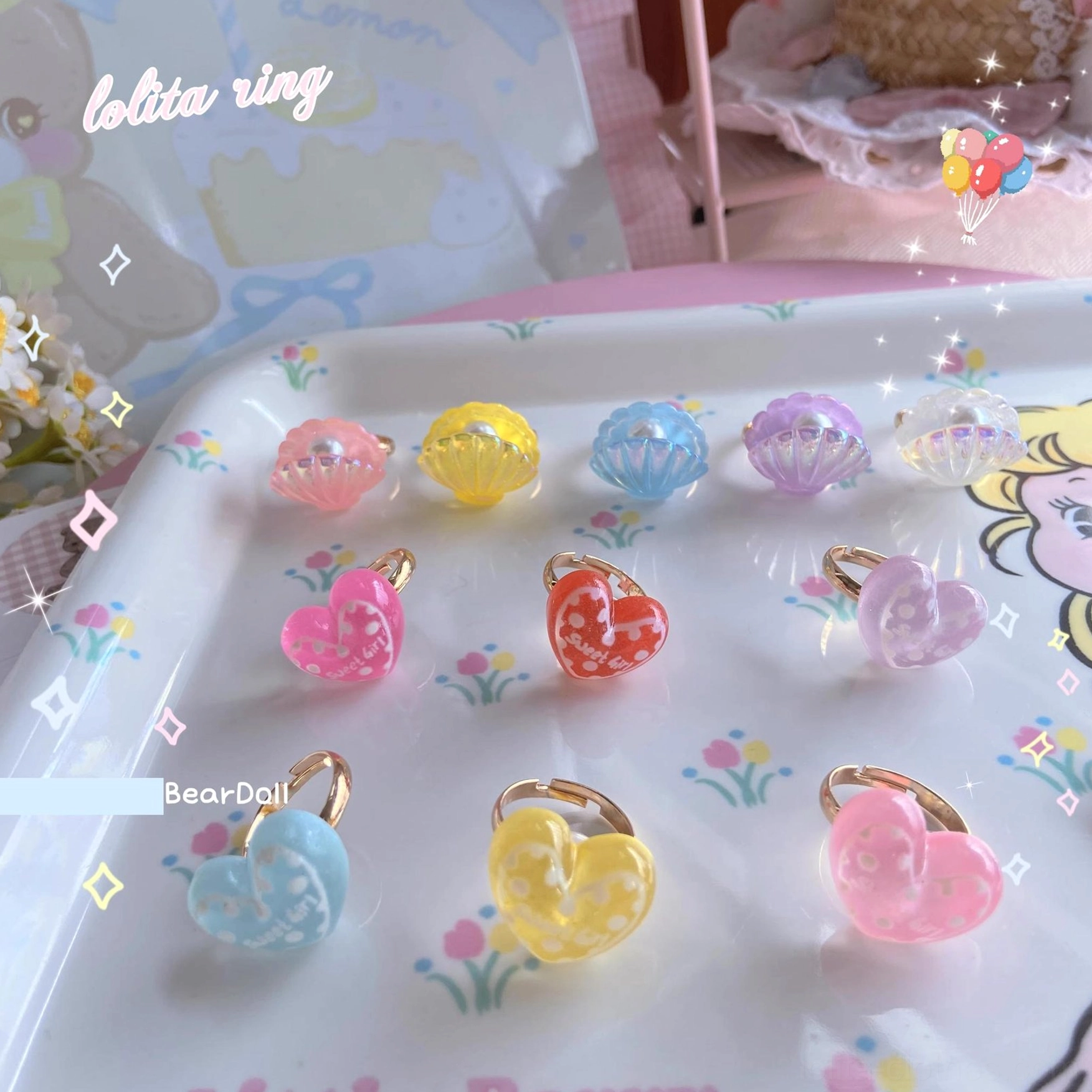 Close-up pastel resin heart Lolita ring charms with gold bands arranged on embossed tulip plate