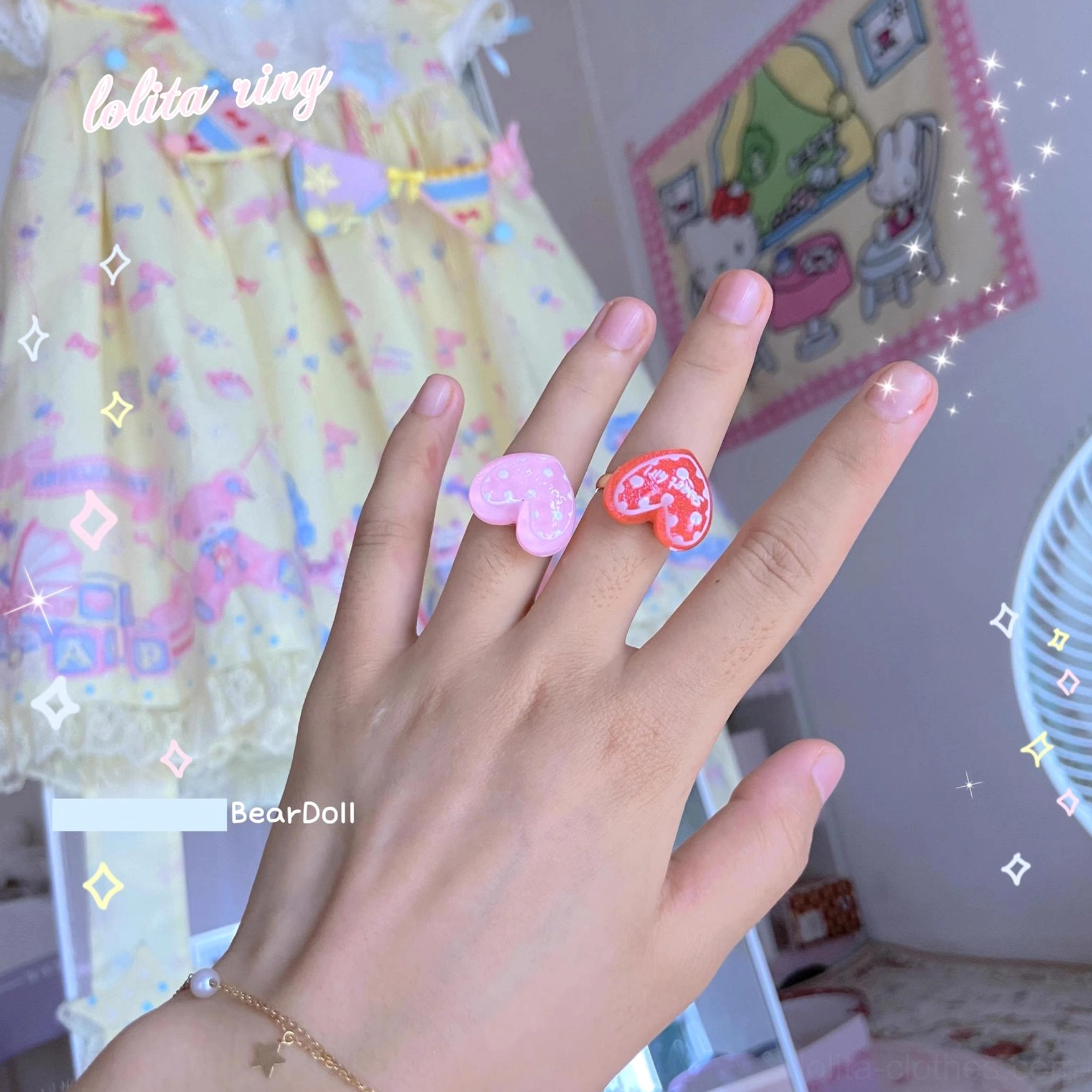 Two pastel heart-shaped resin Lolita rings worn on fingers first-person overhead sweet bedroom backdrop