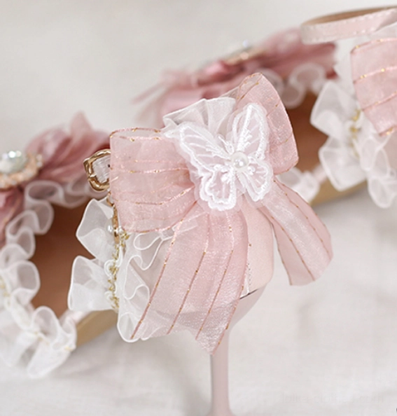 Detailed close-up of ankle strap for pink lolita wedding heels showing pink buckle strap, sheer ruffled trim along strap edge, gold chain with pearl hanging charm, and polished gold buckle hardware
