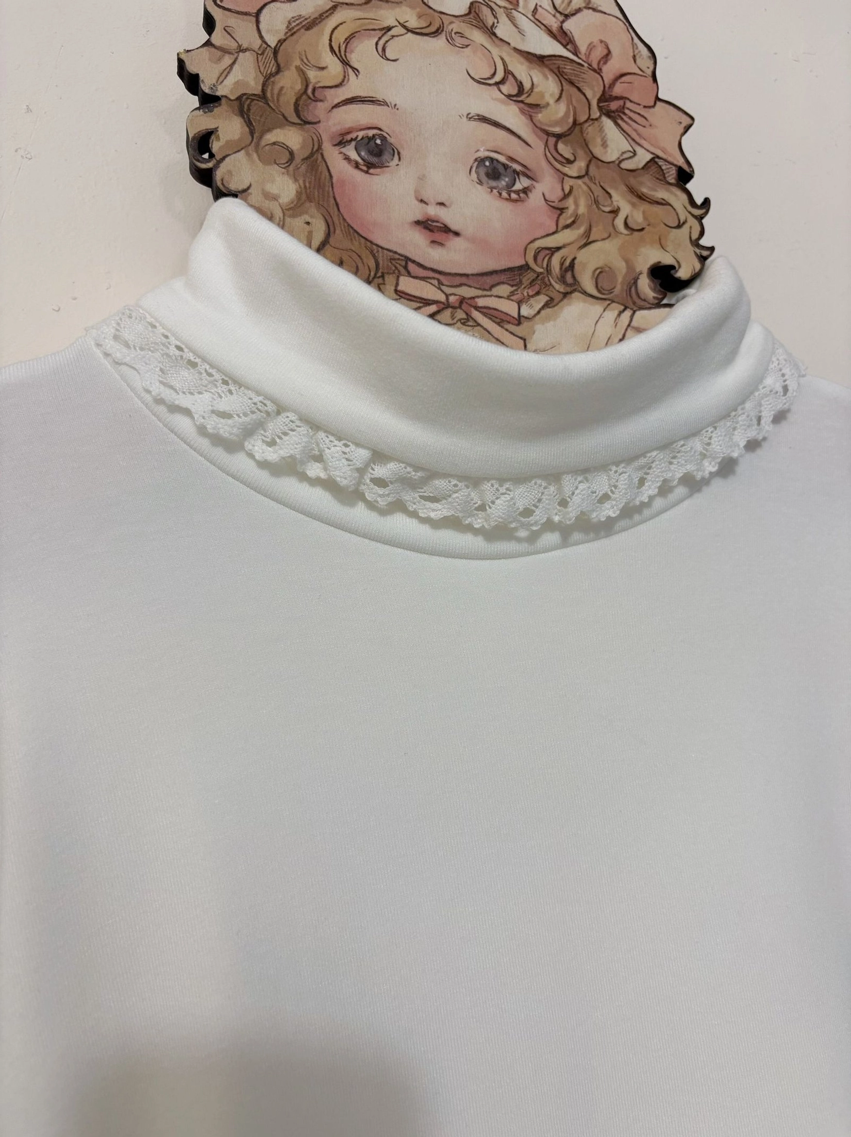 Close-up detail shot of white lolita turtleneck collar with delicate white lace trim and soft smooth knit fabric texture highlighting refined neckline design
