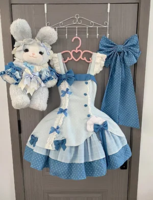 Lolita JSK jumper skirt dress hanging display with matching accessories and plush rabbit doll wearing coordinating mini dress, showcasing polka dot blue bows, ruffled shoulder straps, tiered ruffled hem details