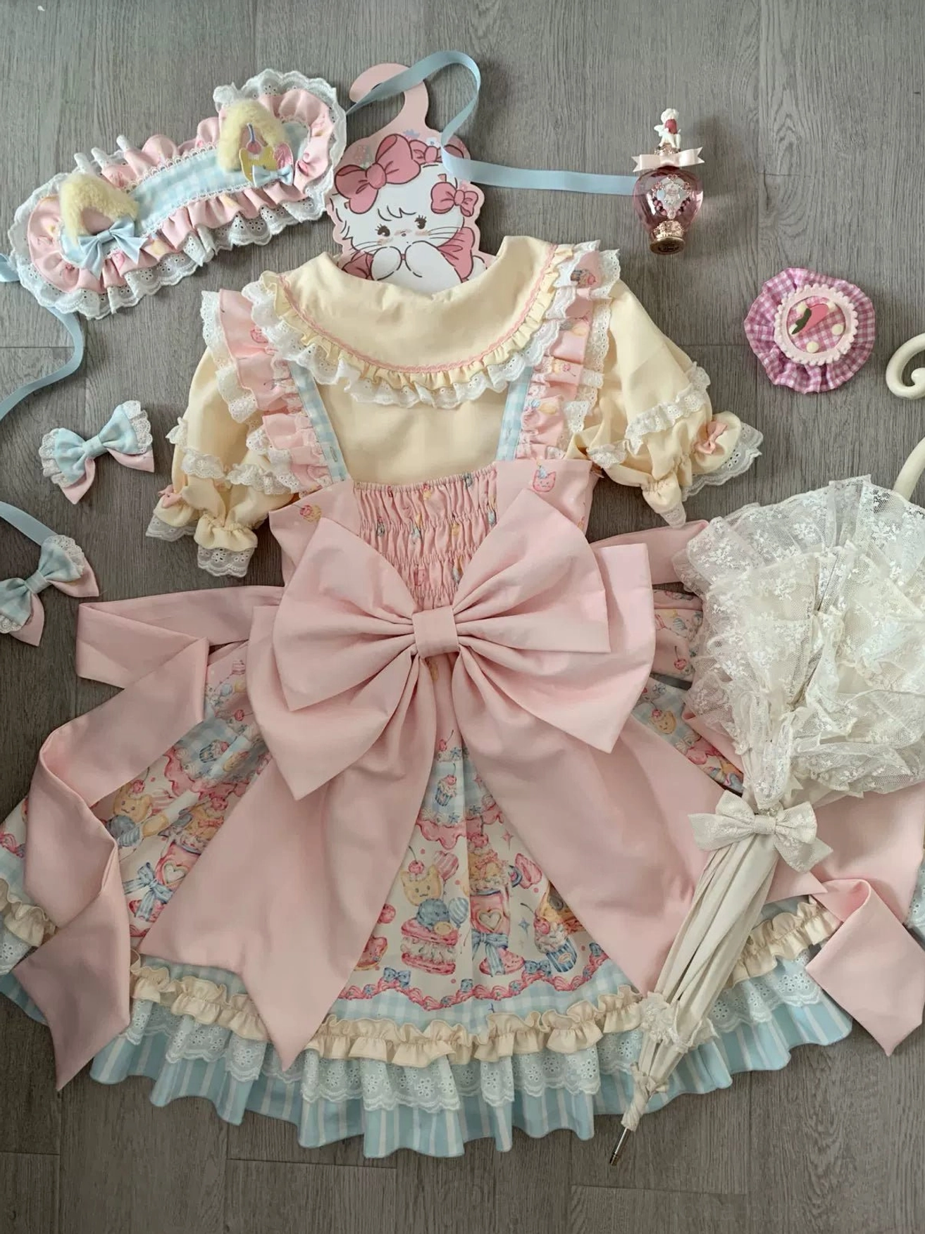 Lolita jsk dress side flat lay view pink bow belt lace parasol mini hair bows pastel color scheme