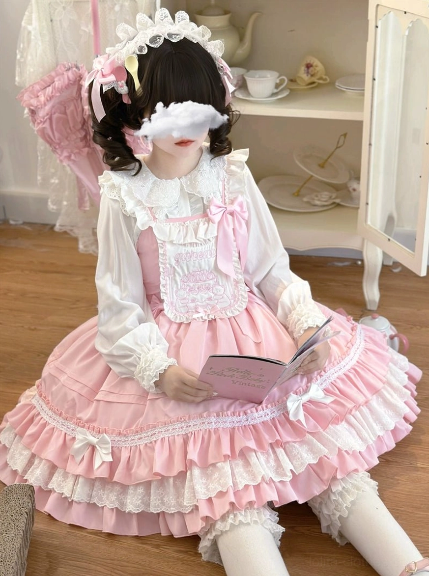 Pink sweet Lolita JSK dress close-up sitting front view wearing lace headbow accessory ruffled collar blouse holding small book plush wing decorations