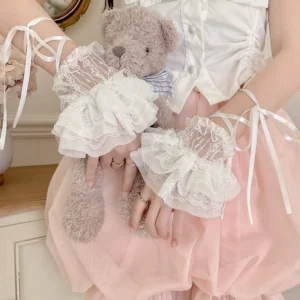 Medium close-up of lolita decorative lace cuffs on model's hands holding teddy bear, featuring sheer floral lace overlay and fluffy chiffon ruffles in cozy vintage home interior styling