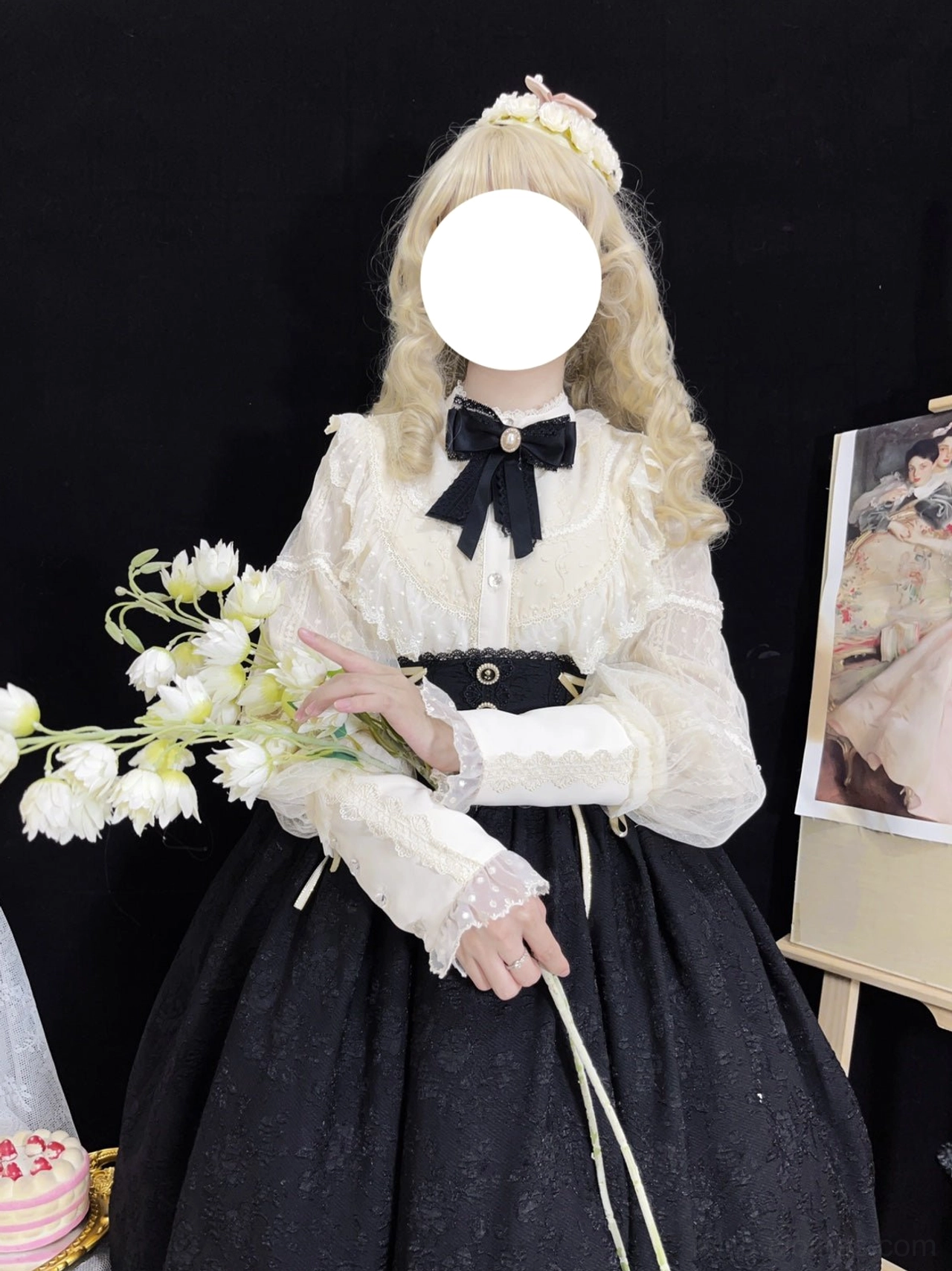 Elegant Lolita daily wear outfit showing cream embroidered blouse with voluminous sleeves and lace cuffs, black high-waisted skirt with ruffled hem, side front oblique view with white flower bouquet and blonde wig model