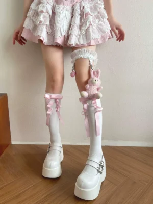 Matching lolita leg accessory set showing white calf socks with pink bows and lace-trimmed thigh garter with plush rabbit pendant displayed from front middle-distance perspective