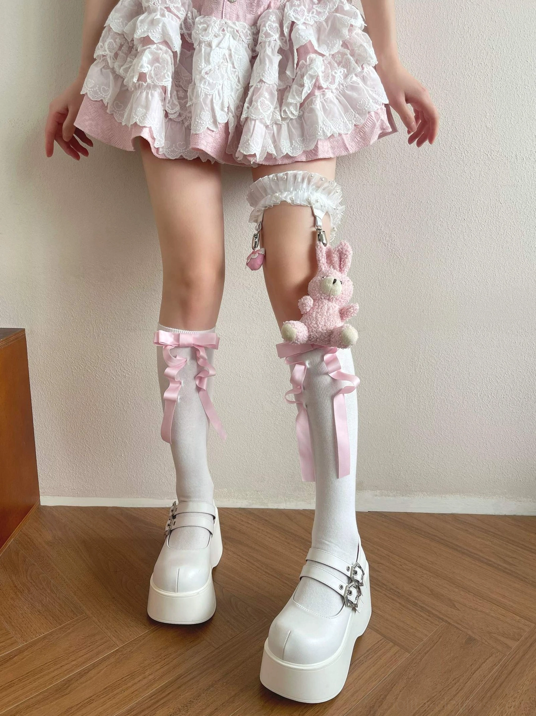 Matching lolita leg accessory set showing white calf socks with pink bows and lace-trimmed thigh garter with plush rabbit pendant displayed from front middle-distance perspective