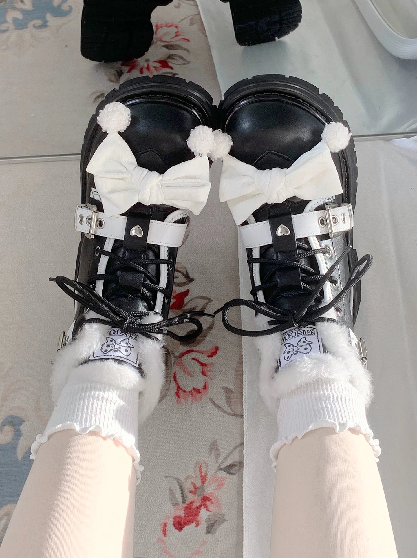 Pair of lolita winter martin boots symmetrical bow ornaments thick lug soles matching silver buckle straps first-person downward view