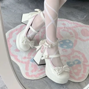 White patent leather Lolita Mary Jane high heel shoe worn on foot with cross-patterned sheer thigh-high stockings, close-up side view showing ankle strap with heart buckle, bow lace trim, and platform block heel