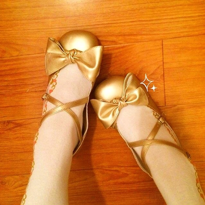 Champagne gold lolita bow cross-strap leather shoes top-down flat lay with stockings wooden floor background