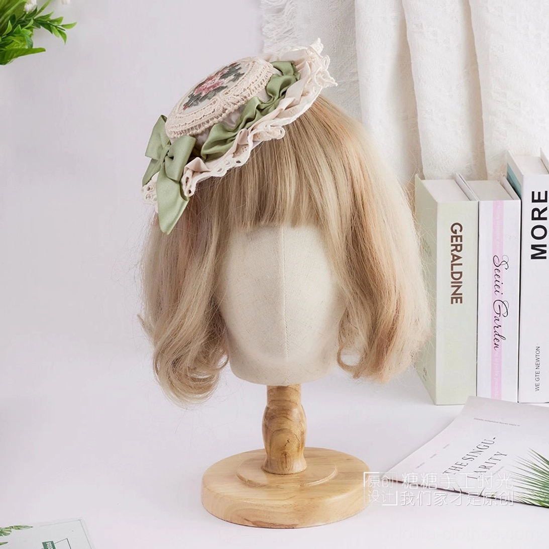 Side profile view of delicate Lolita top hat showing sage green bow, petit floral embroidery detail, and hand-finished white lace trim construction