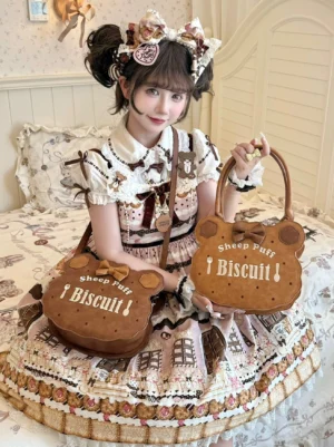 Lolita model sitting on bed showcasing two different styles of kawaii cookie-themed handbags with embroidered details and 3D bow embellishments