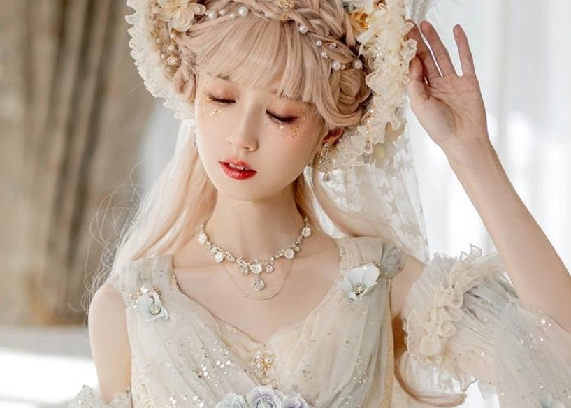 Side profile of Lolita model wearing floral bonnet hat and bridal veil, soft warm indoor lighting with chandelier background