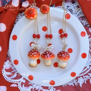 Close-up top-down view of fly agaric themed lolita necklaces featuring glossy red mushroom caps with white spots and delicate white bow accents arranged on polka dot plate with lace trim and red fabric background