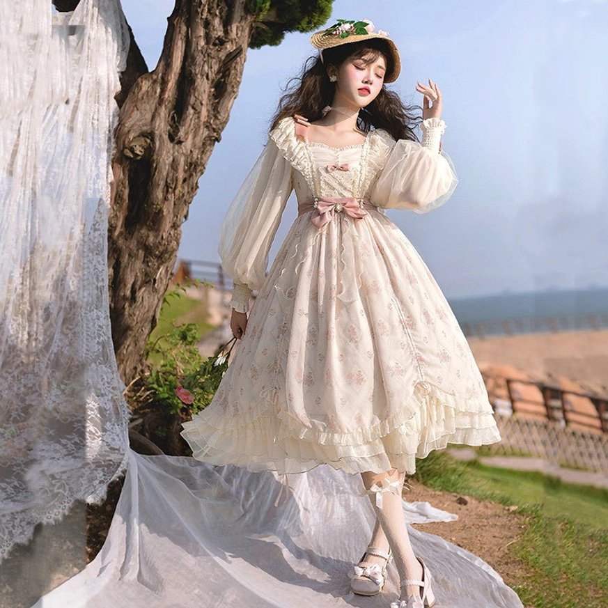 Elegant lolita OP dress back view featuring subtle pink floral print, sheer puff sleeves, pink waist bow, layered tulle skirt with romantic silhouette, seaside outdoor setting