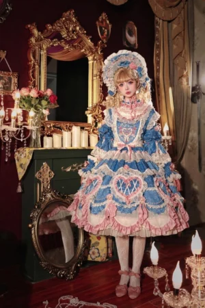 Full front view of tiered cake-style blue-pink Lolita OP dress with heart-shaped waist decoration, ruffled lace layers, matching bonnet and pink bow shoes in vintage bedroom with gilt mirror