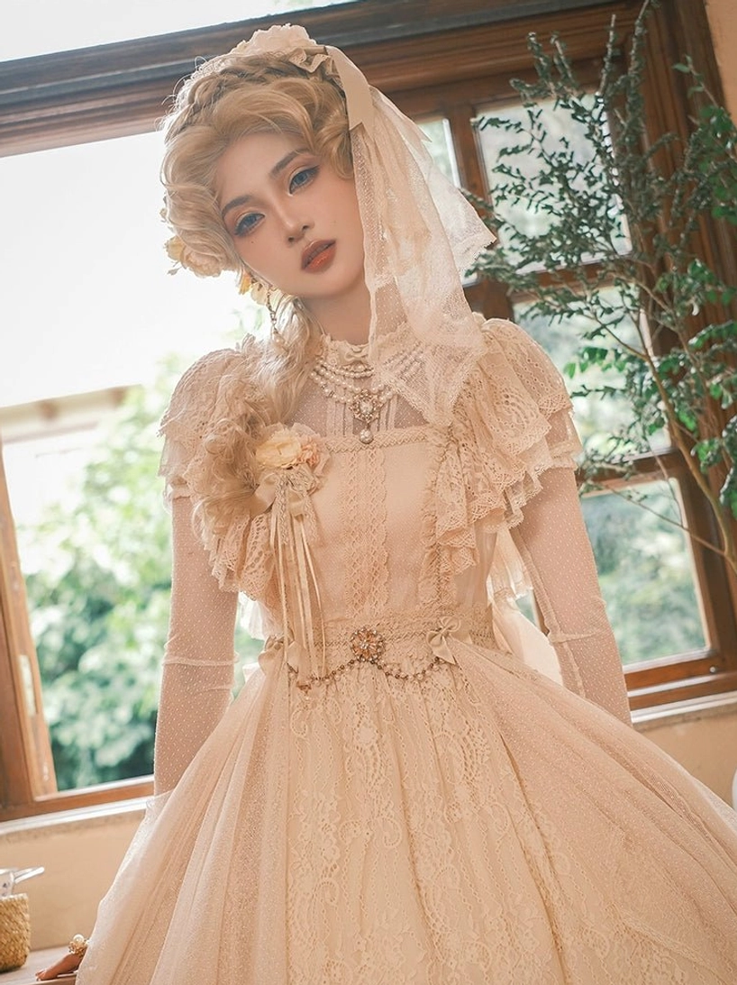 Champagne vintage Lolita OP dress close-up half-body front view, model with veil near outdoor green plants, square neckline, pearl waist chain, ruffled chest floral decor, layered pearl necklaces and sheer wrist cuffs