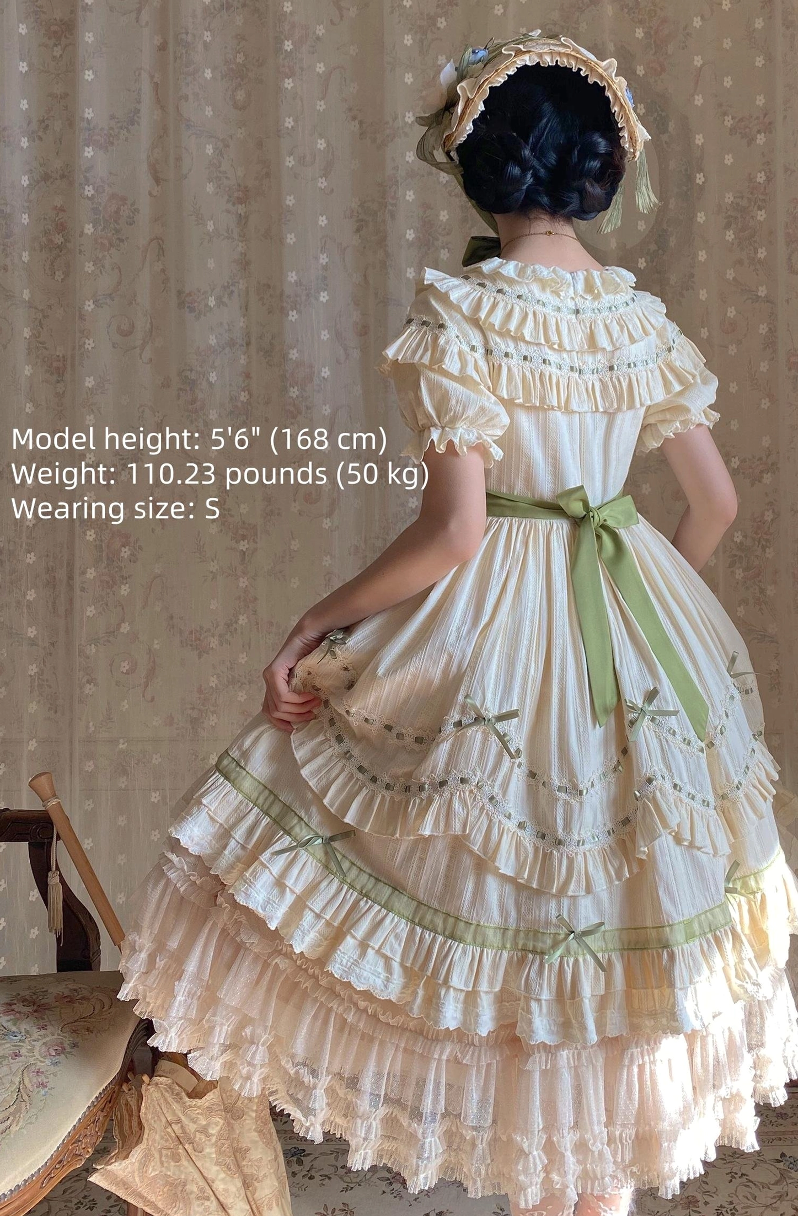 Full back view of lily of the valley country lolita OP dress showing green waist sash and layered ruffle skirt with tiered green trims and short ruffled sleeves
