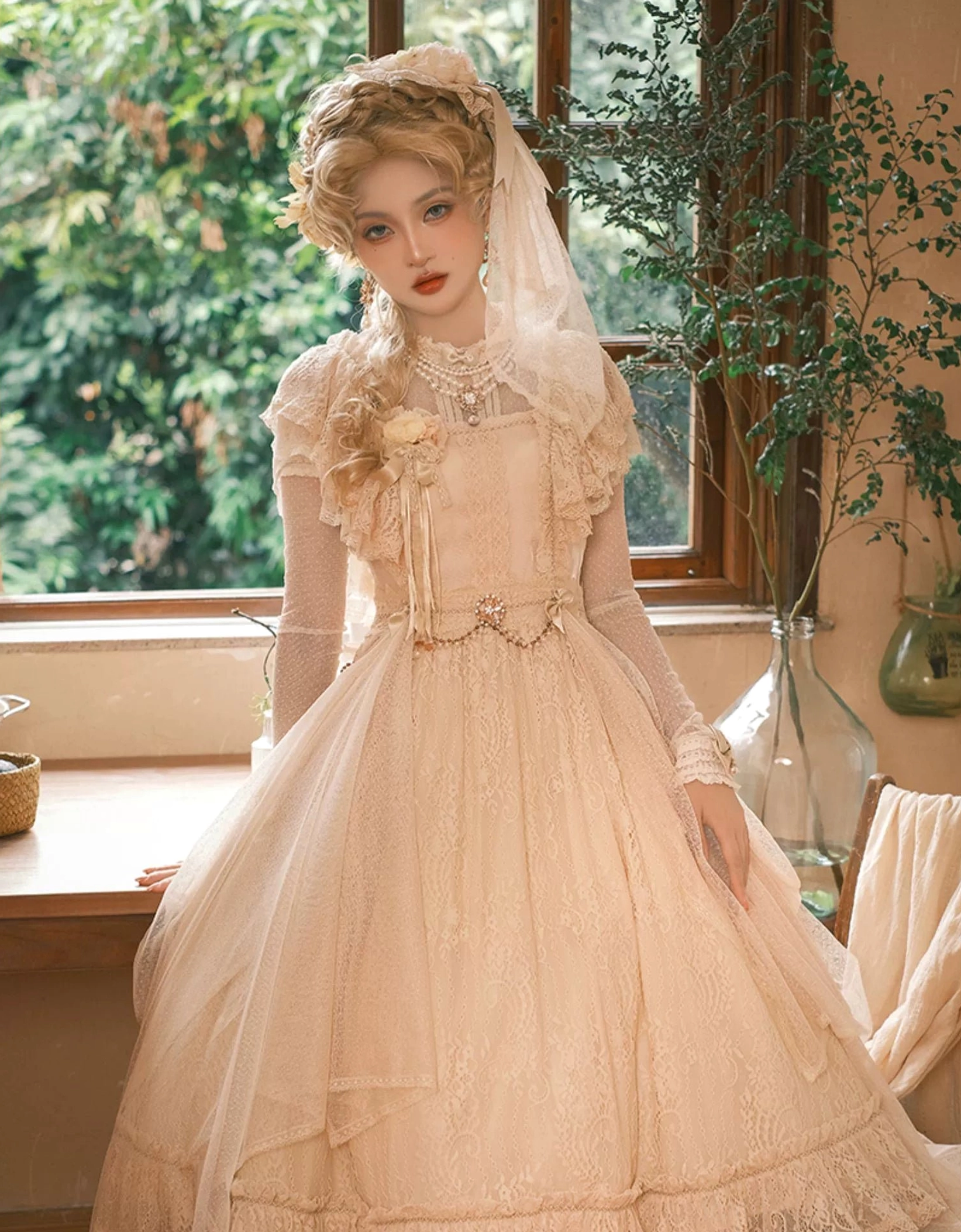 Champagne Lolita OP dress full-length three-quarter view by outdoor window in garden-side sunlit dining space, tulle overskirt, pearl waist belt, sheer wrist cuffs, veil headwear and chest floral decoration
