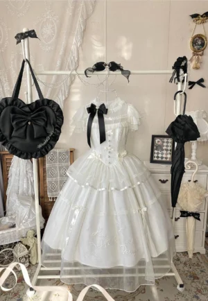 Classic lolita OP dress displayed on vintage clothing rack with black heart-shaped handbag and mini umbrella accessory, front hanging view