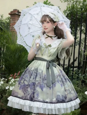 Elevated front full view of sage green lolita OP dress on model, height 5'3 wearing size S, showing sheer V-neck with lace trim, ruffled short sleeves, layered ruffled skirt hem and coordinated hairband