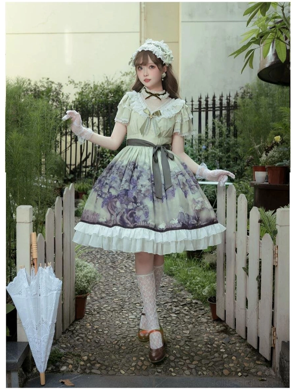 Front three-quarter view of grape manor lolita OP dress on model adjusting lace parasol in garden setting, showing matching hair accessory, white ruffled hem, grey waist sash and complete classic lolita silhouette