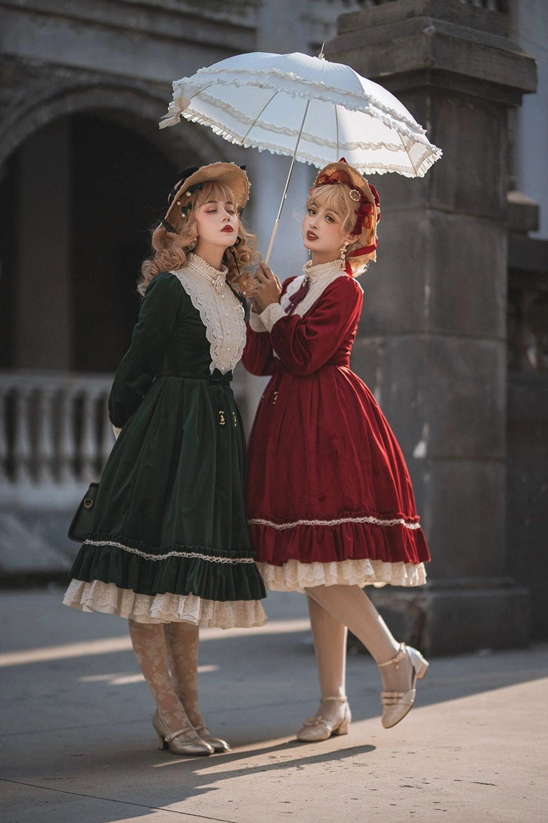 Vintage velvet lolita OP dress side rear full-body group shot stone arch street outdoor area two models with lace parasol solid soft velvet fabric ruffled skirt white lace edge