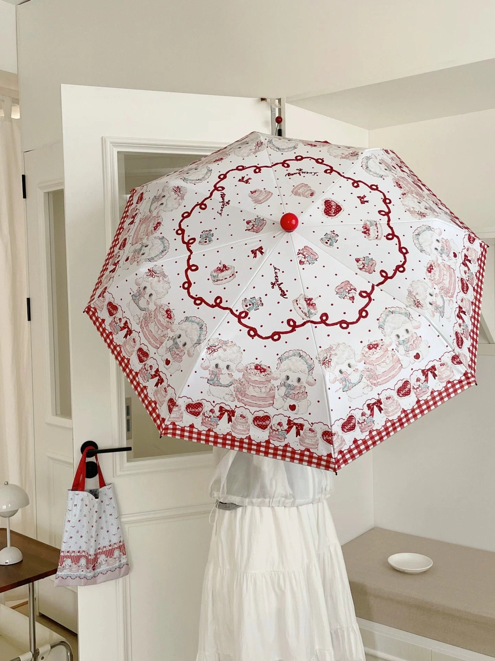 Reverse side of red-trimmed lolita parasol with white base showing dessert and animal prints and red border design