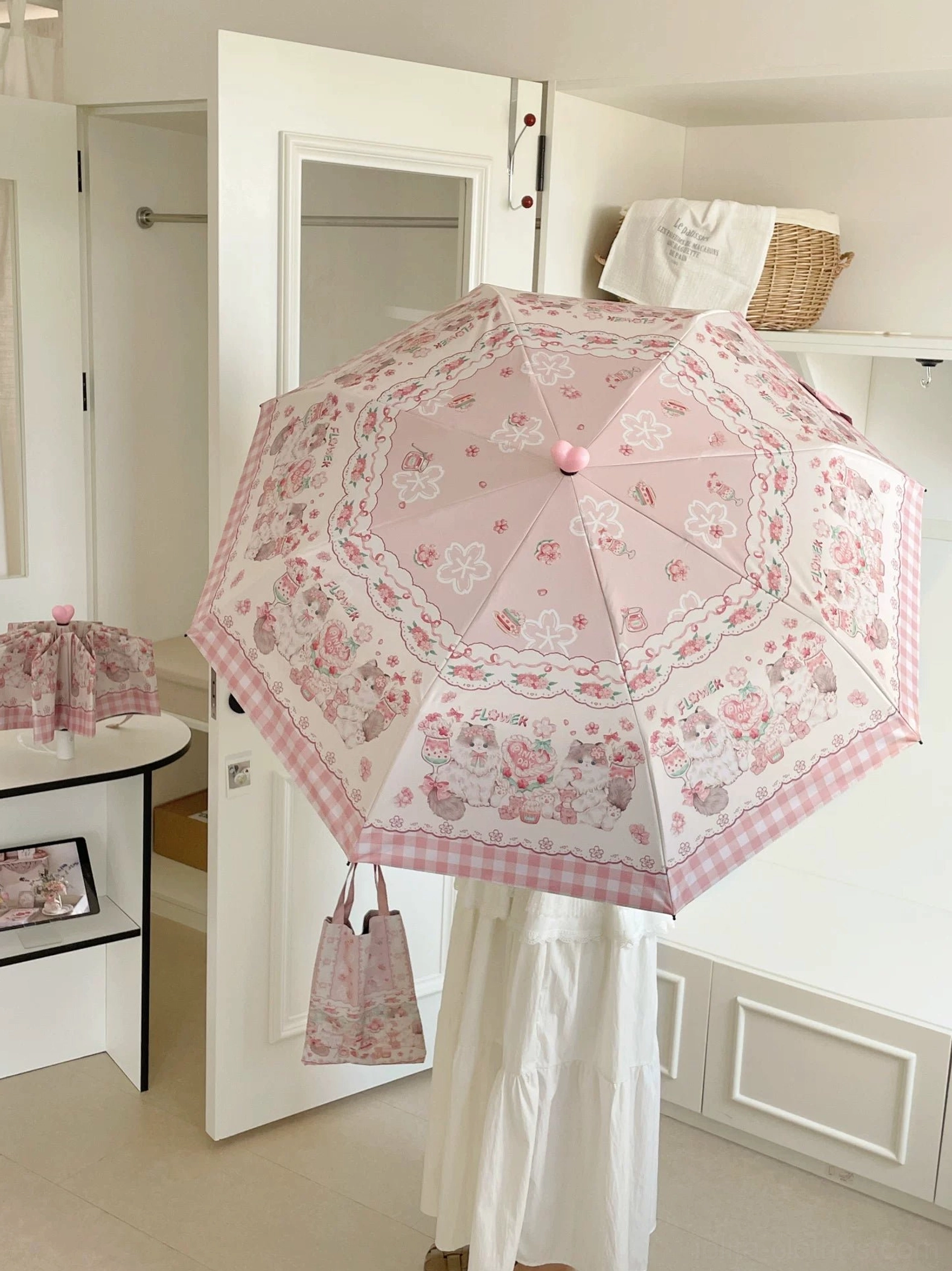 Overhead view of pink lolita foldable parasol with cute cartoon prints and gingham trim fully opened on white background