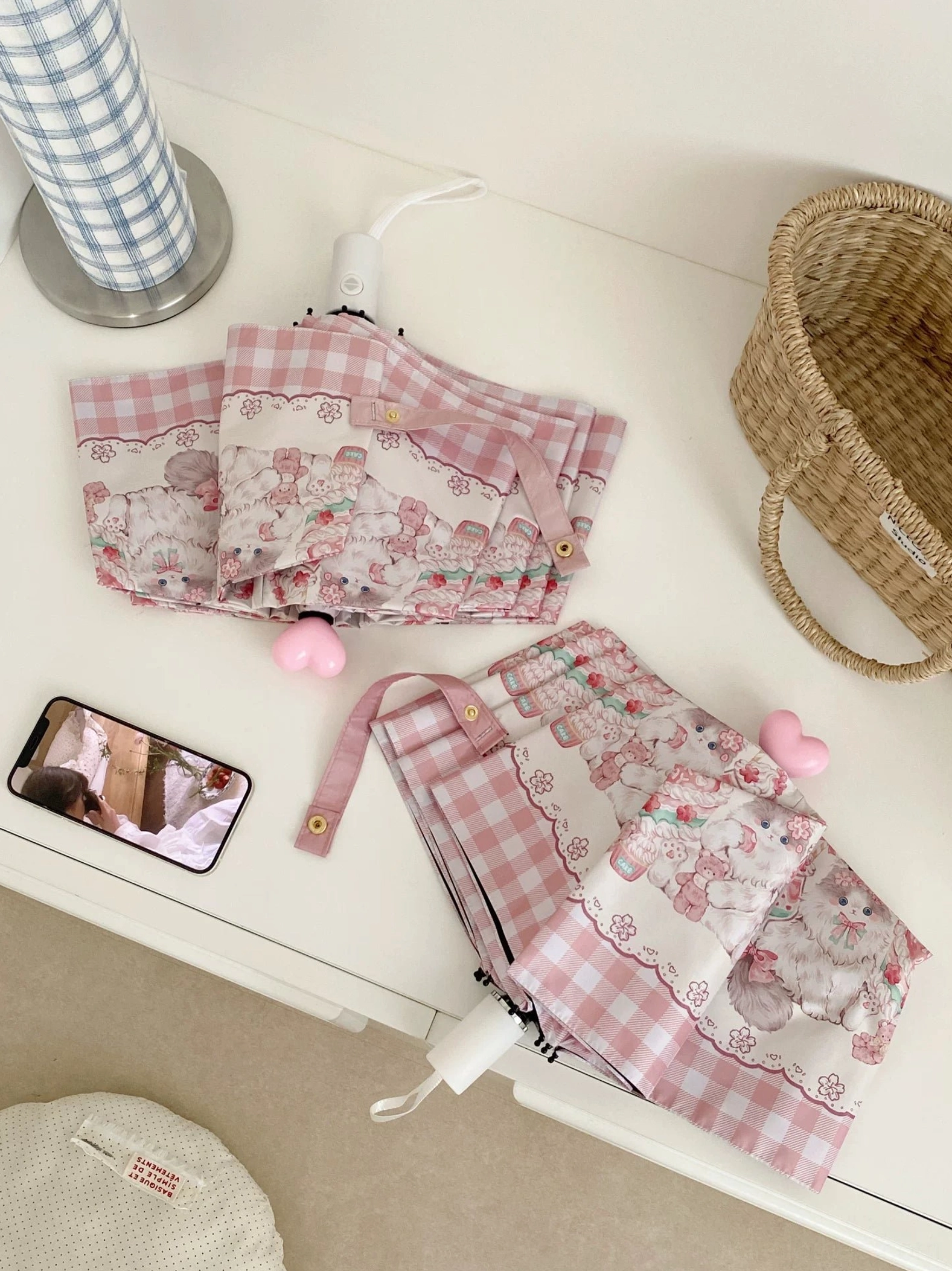 Red-trimmed lolita parasol with matching printed tote bags on round white table cozy bedroom setting