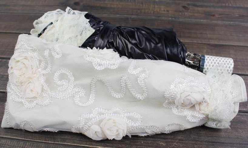 Product photography of foldable lolita parasol showing wooden handle with decorative tassel and crystal charm, octagonal canopy structure, and delicate lace embroidery detailing